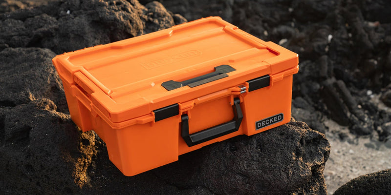 Blaze Orange DECKED Halfrack 32 closed on black lava rock at sunrise