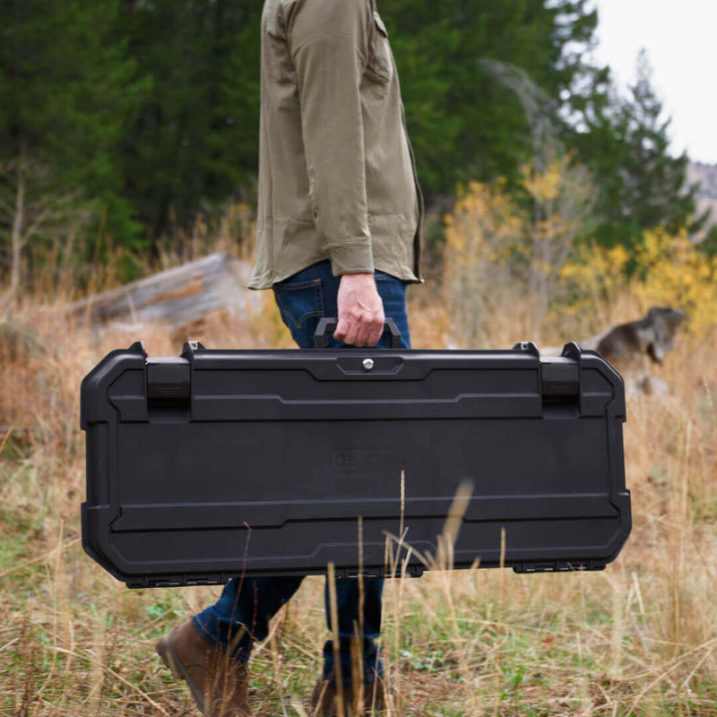 Man carrying a closed Black DECKED Honcho 80 by its top handle across an autumn field