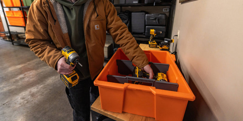 Owner setting cordless tools into a Blaze Orange DECKED Payloader 32 fitted with optional divider panels