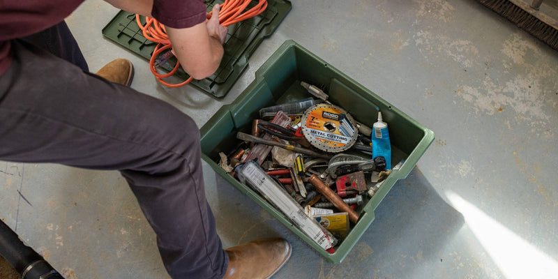 Ranger Green DECKED Payloader 32 loaded with plumbing tools on a shop floor with its lid set aside
