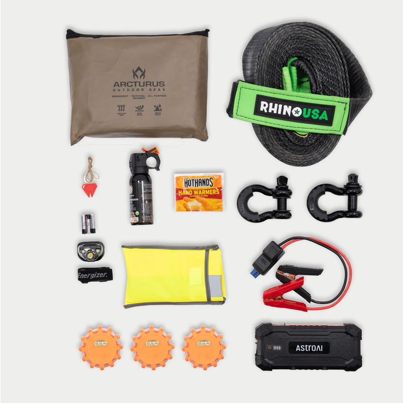 Flat lay of every item in the DECKED Roadside Emergency OS Kit, including the jump pack, tow strap, shackles, LED road flares, fire suppressor, survival blanket, safety vest, headlamp, hand warmers and whistle