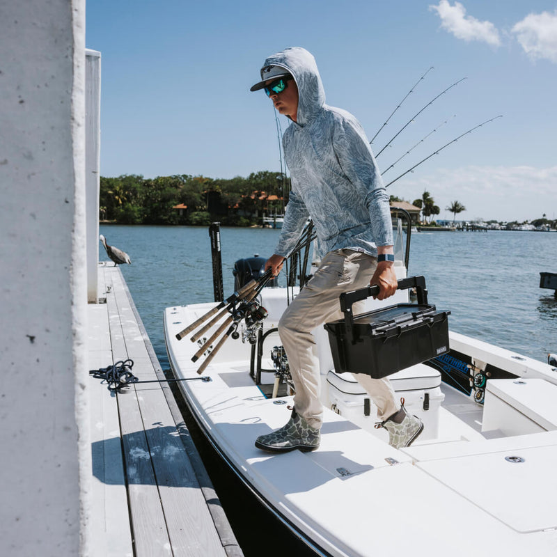 Angler carrying the Black DECKED Sixer 16 by its lid handle off a boat