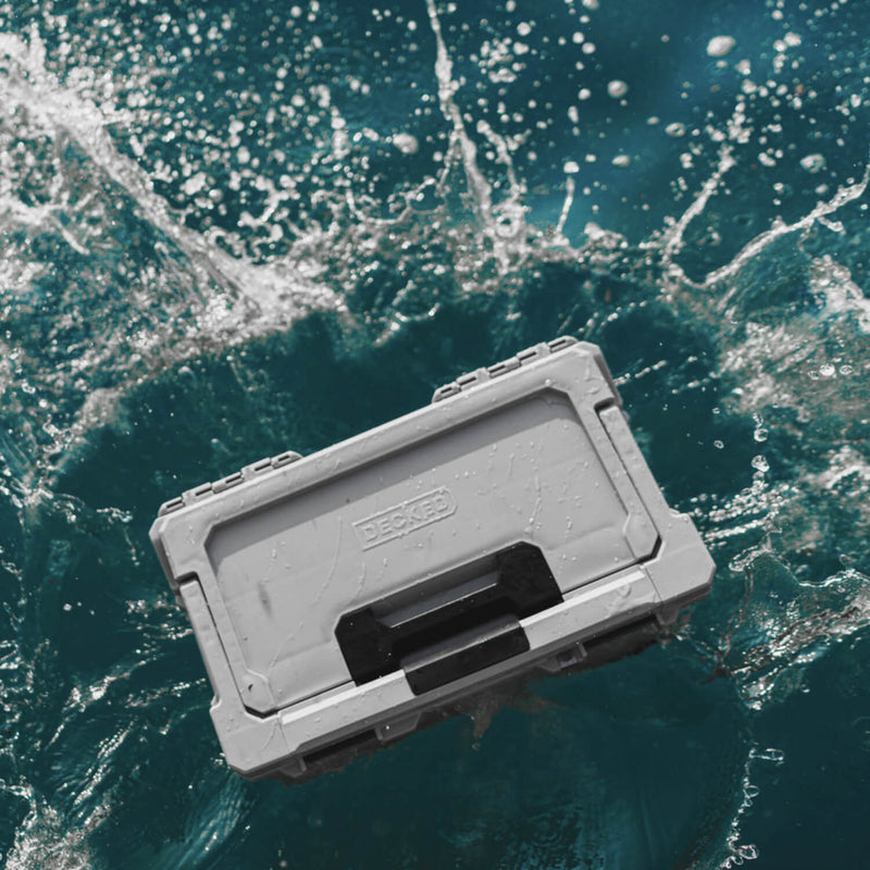 Cool Gray DECKED Sixer 16 closed and taking a wave of water from above, showing the sealed lid