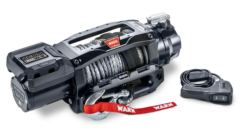 Warn ZEON XC 10-S winch from an angle showing the low-profile control pack, drum and clutch lever, with the corded remote alongside