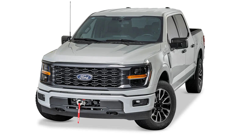 Silver Ford F-150 photographed head-on with the Warn hidden winch installed behind the factory bumper, only the fairlead and rope visible at the lower valance