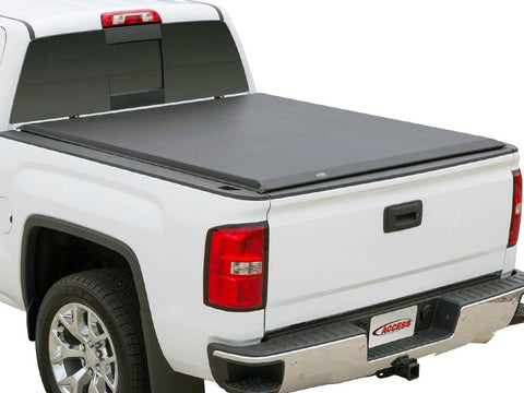 Rear three-quarter studio view of a white pickup with a black soft roll-up cover closed flat over the bed, Access logo plate