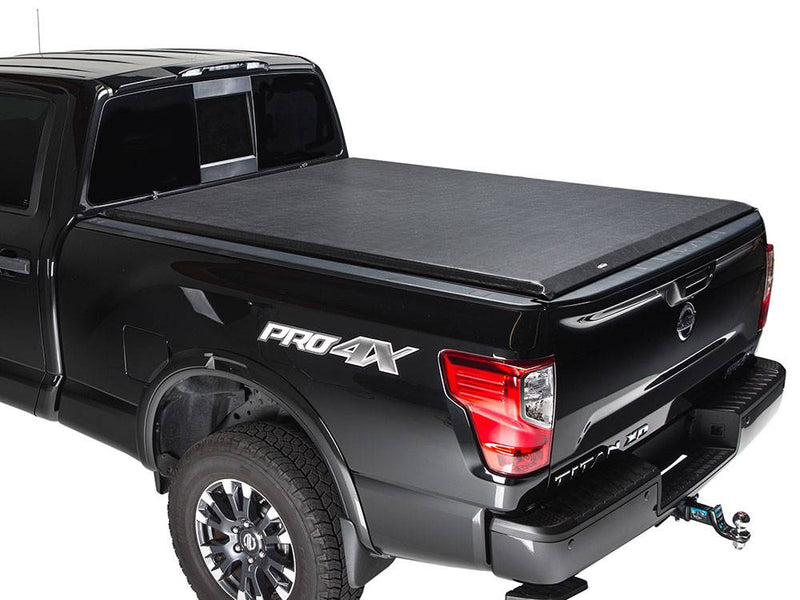 Black pickup on a white background with a black roll-up tonneau cover closed flat over the bed