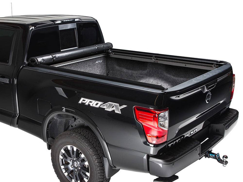 Black pickup with the cover rolled all the way to the cab, carpeted bed fully open, white background