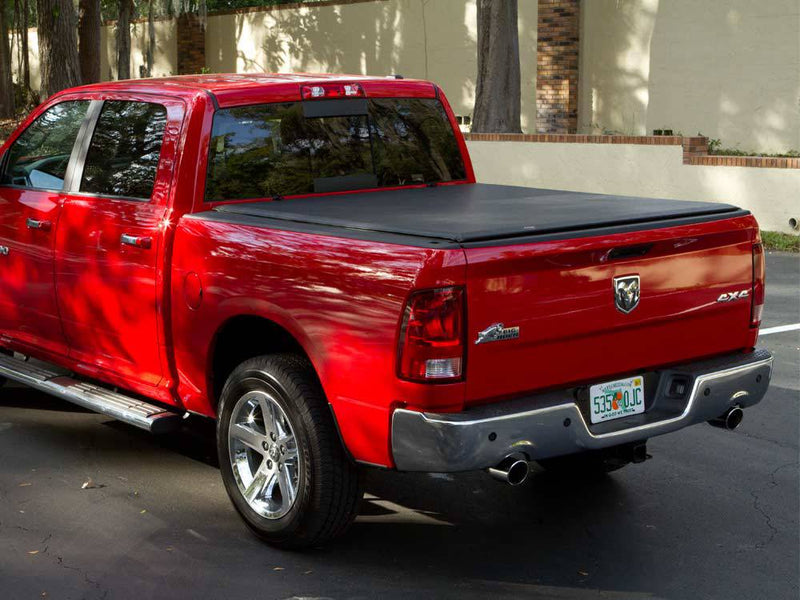 Red crew cab pickup parked on a street with a black roll-up tonneau cover closed flat, tailgate up