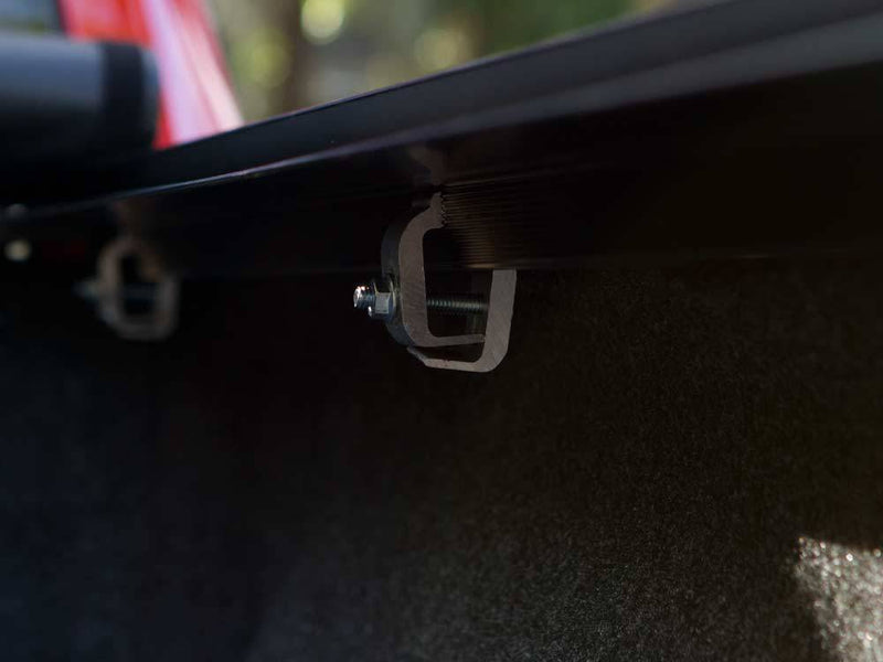 Dim view inside the bed of a side-rail mounting clamp bolted under the bed rail