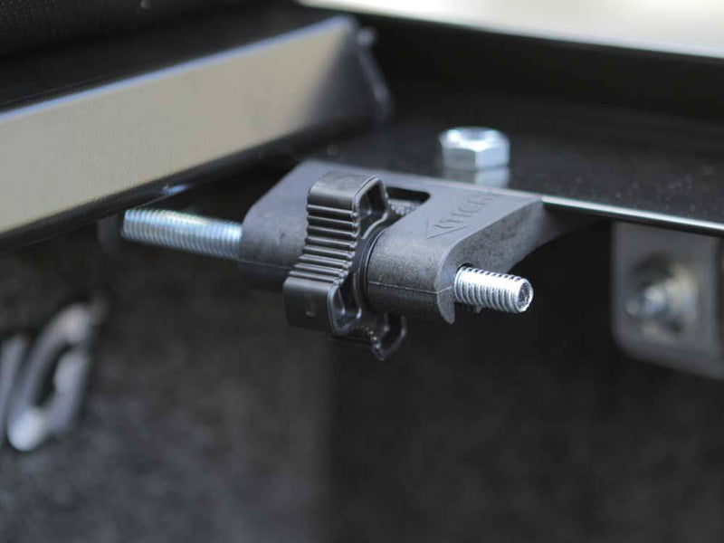 Close-up of a black side-rail mounting clamp with its bolt and nut under the bed rail