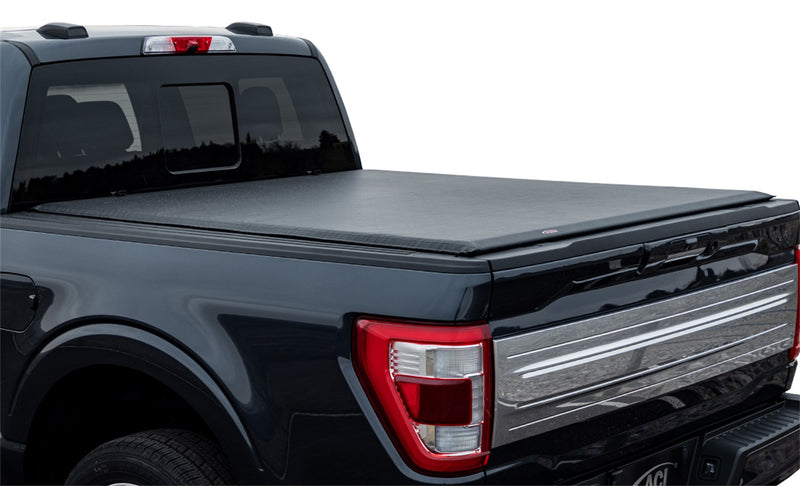 Full view of the Access Lorado roll-up tonneau cover: dark blue pickup with a black vinyl roll-up cover closed flat over the bed, white background