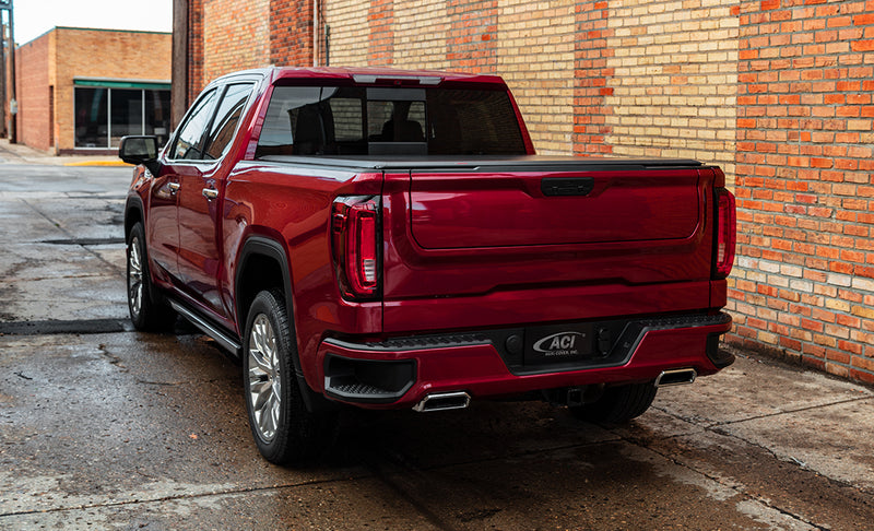 Access Lorado roll-up tonneau cover on a pickup bed: red crew cab pickup by a brick wall with a low black roll-up cover closed flush over the bed (running boards shown, not included)