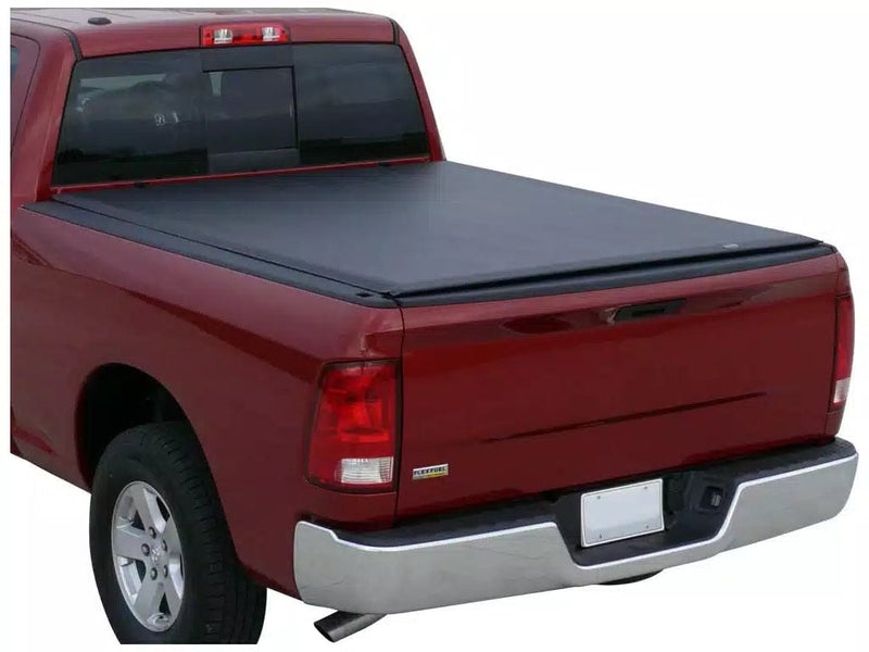 Full view of the Access Lorado roll-up tonneau cover: red pickup on a white background with a black vinyl roll-up cover closed flat over the bed