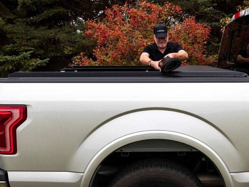 Man rolling the vinyl tonneau cover up from the tailgate end toward the cab