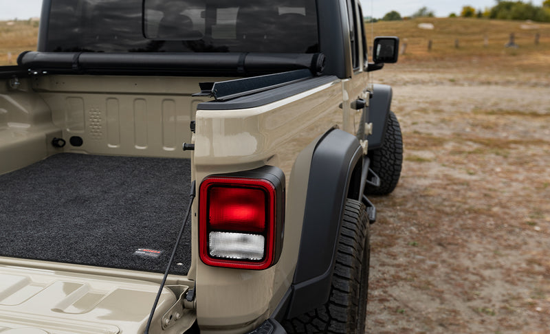 Access Original roll-up tonneau cover on a pickup bed: roll-up cover rolled tight against the cab over an open bed with a carpet bed mat, tan pickup rear quarter (bed mat shown, not included)
