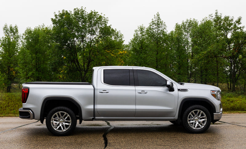 Access Original roll-up tonneau cover on a pickup bed: silver crew cab pickup in side profile with a low black roll-up cover closed flush over the bed