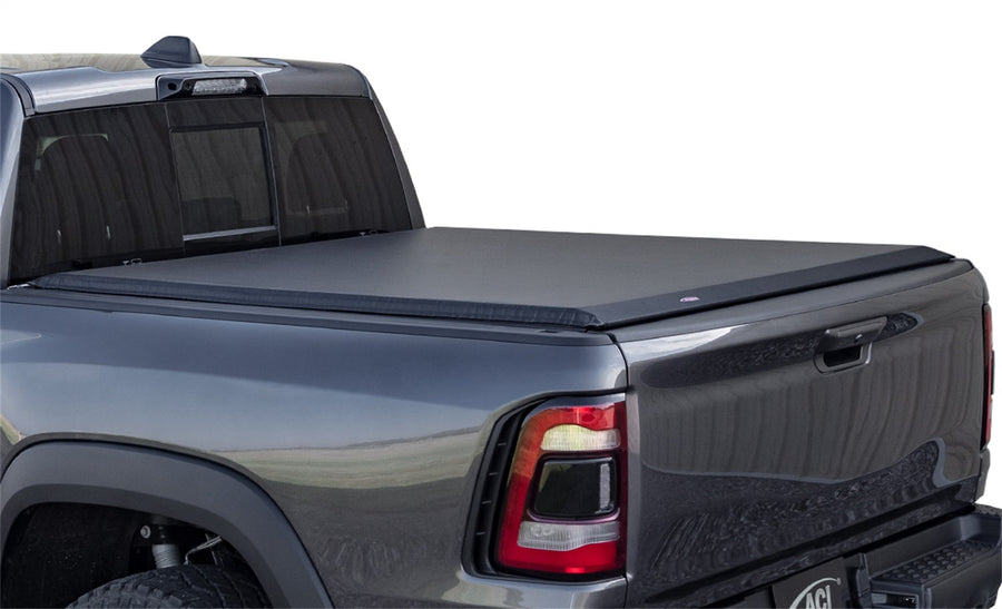 Access roll-up tonneau cover: Gray pickup on white with a black vinyl roll-up cover closed flat over the bed, rear three-quarter