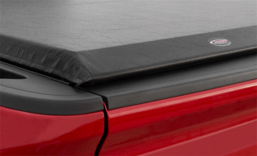 Access Original roll-up tonneau cover: Close-up of a closed black vinyl roll-up cover's rear corner and side rail on a red pickup