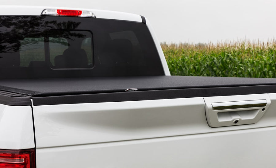 Access TonnoSport roll-up tonneau cover: Close side view of a white pickup bed with a low-profile black cover closed flush with the rails