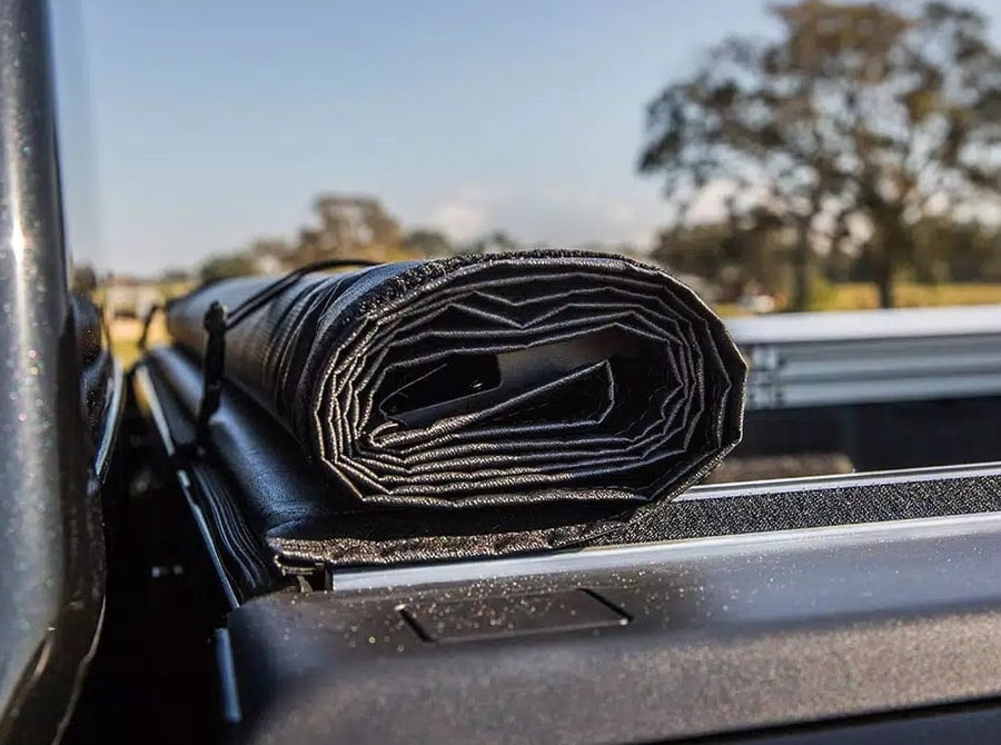 Access TonnoSport roll-up tonneau cover: Vinyl roll-up cover rolled at the cab and held by storage straps, seen along the bed rail