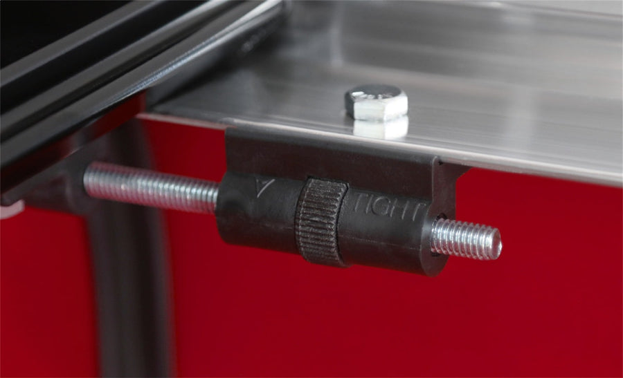 Access TonnoSport roll-up tonneau cover: Threaded tension adjuster knob mounted on a side rail over a red bed wall