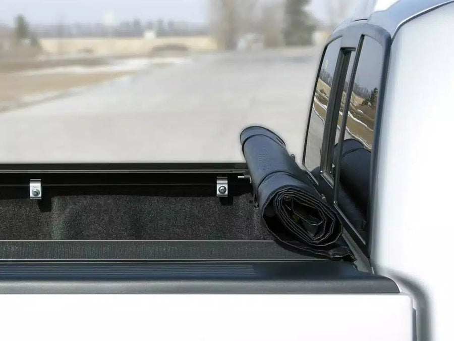 Access LiteRider roll-up tonneau cover: Roll-up cover rolled and strapped at the front of an open pickup bed, rails visible along both sides