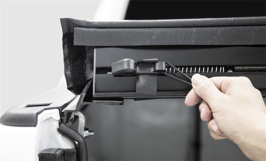 Access LiteRider roll-up tonneau cover: Hand pulling the latch cord at the rear of a vinyl roll-up cover