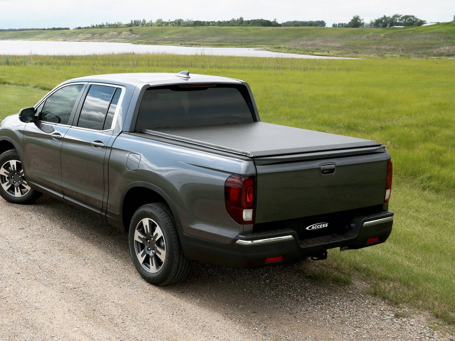 Access roll-up tonneau cover: Gray crew cab pickup by a lake with a black roll-up cover closed over the bed