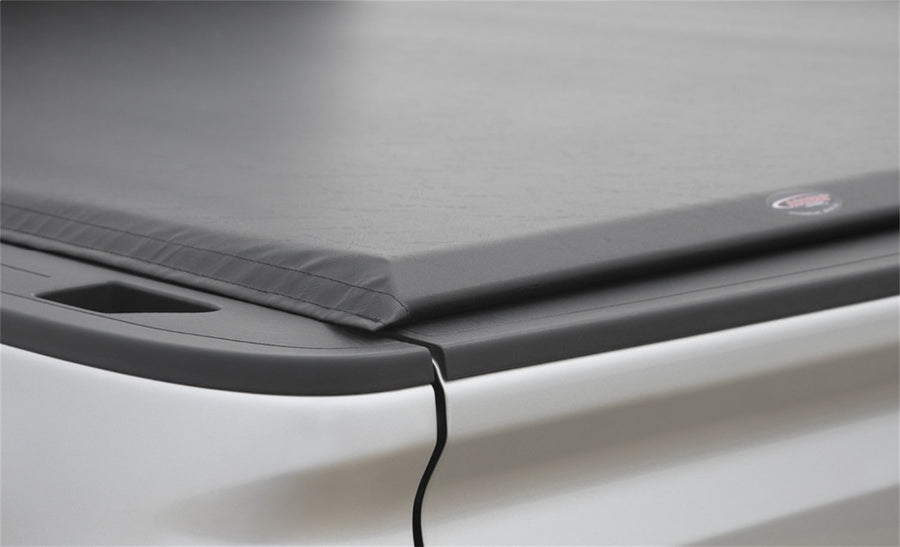 Access Lorado roll-up tonneau cover: Close-up of a black roll-up cover's rear corner on a low rail with a release cord hanging down