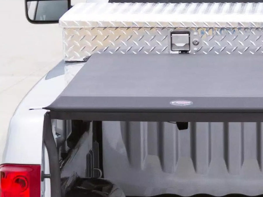 Access Toolbox Edition roll-up tonneau cover: Close-up from the open tailgate of a black roll-up cover closed flat, ending at an aluminum diamond-plate bed toolbox