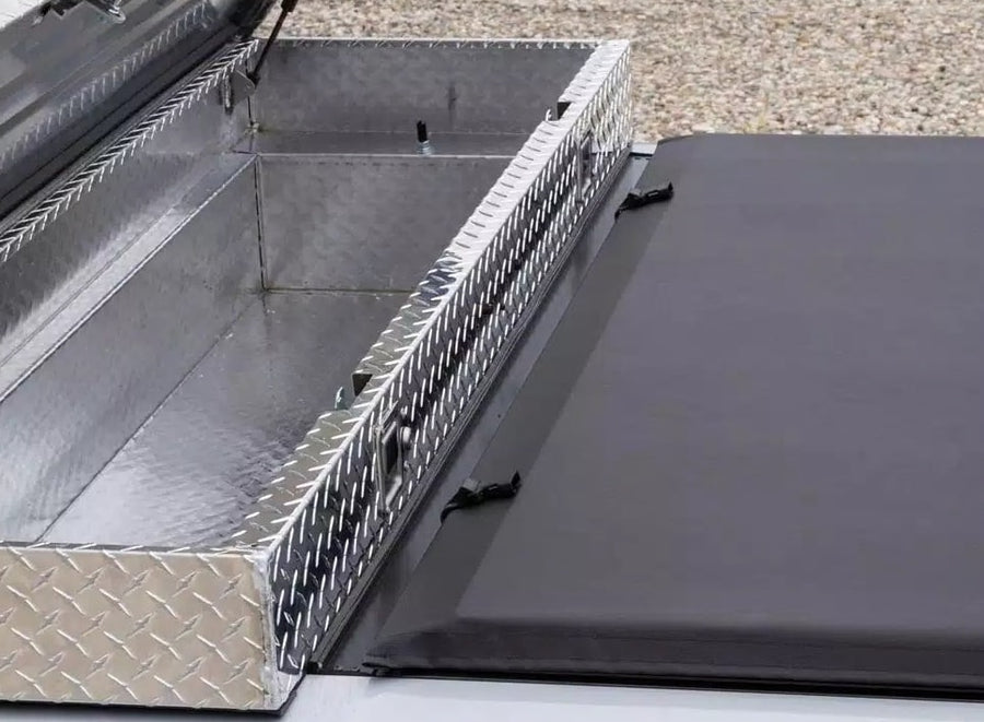 Access Toolbox Edition roll-up tonneau cover: Overhead close-up of an open aluminum diamond-plate bed toolbox beside the front edge of a closed black roll-up cover