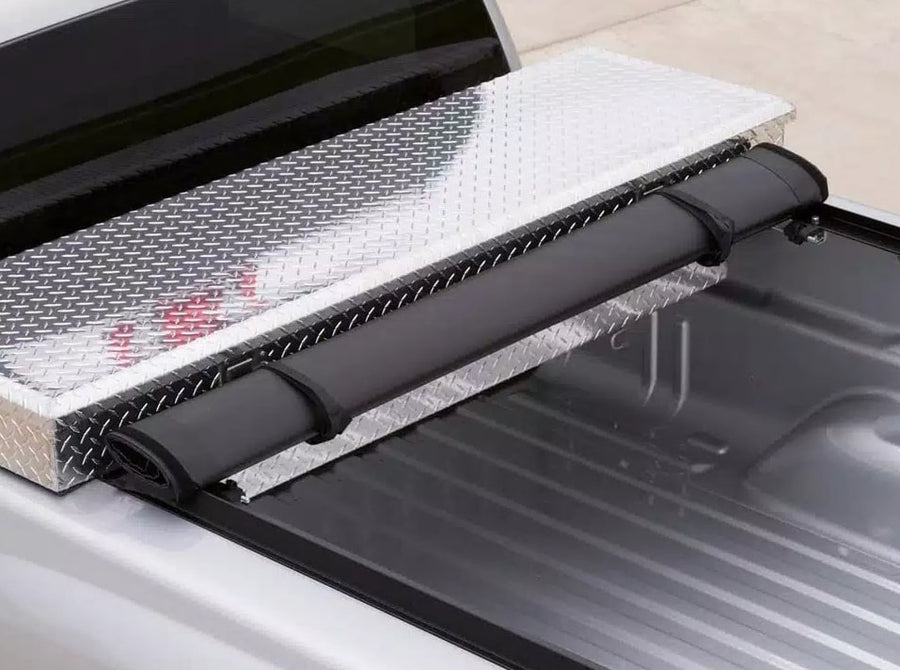 Access Toolbox Edition roll-up tonneau cover: Close-up of a black roll-up cover rolled and strapped against an aluminum diamond-plate bed toolbox