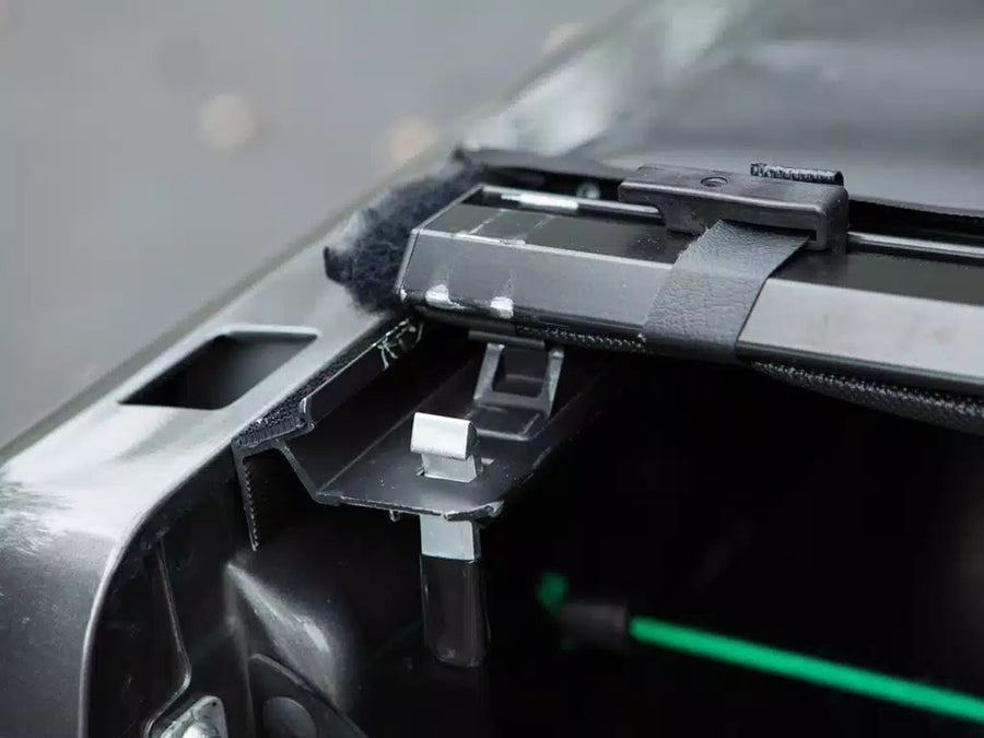 Access Vanish roll-up tonneau cover: Close-up of aluminum side rail hardware and clamp at the rear corner of a pickup bed, green cable below