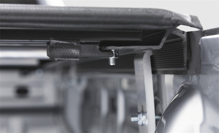 Access Vanish roll-up tonneau cover: Close-up of the lifted rear edge of a black roll-up cover showing the side rail and latch hardware