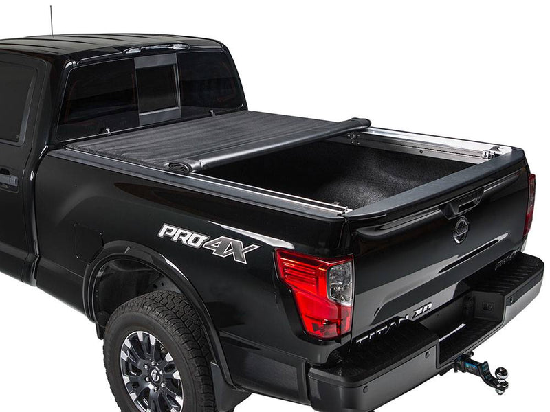 Black pickup on a white background with the roll-up cover rolled halfway toward the cab, rear bed open