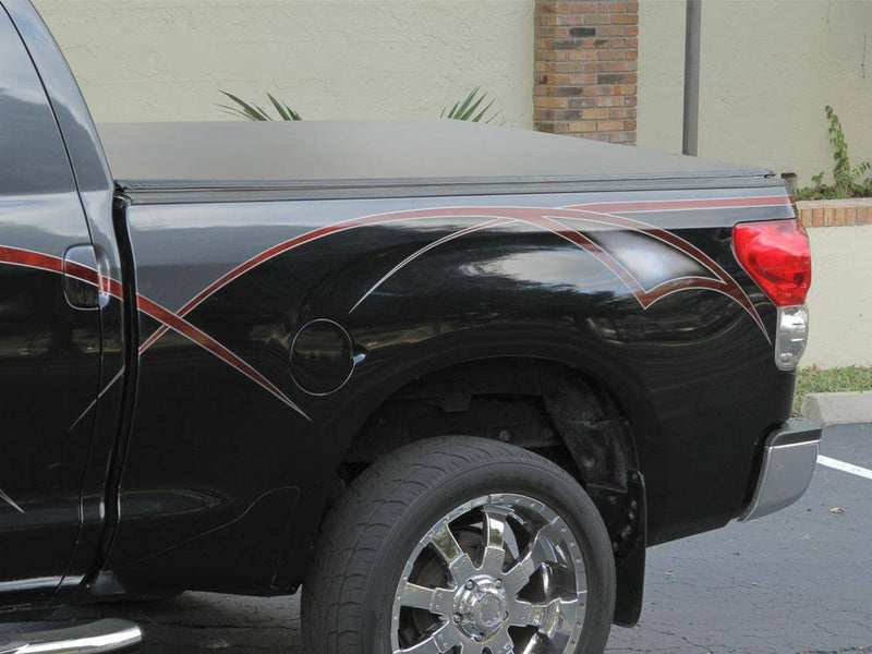 Side view of a black pickup bed with pinstripe graphics and a black roll-up cover closed over it