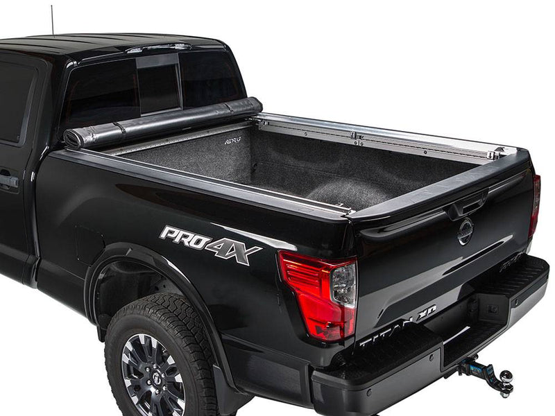 Black pickup on a white background with the cover rolled all the way to the cab, carpeted bed fully open