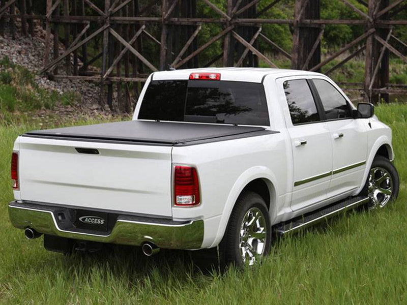 White pickup parked on grass with a black roll-up tonneau cover closed over the bed