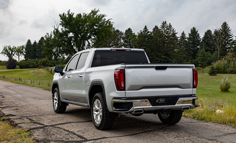 Access TonnoSport roll-up tonneau cover on a pickup bed: silver crew cab pickup on a rural road with a low-profile cover closed flat over the bed