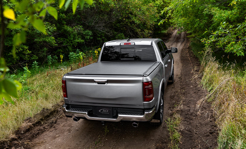 Access TonnoSport roll-up tonneau cover on a pickup bed: silver pickup on a wooded dirt trail, low-profile roll-up cover closed over the bed
