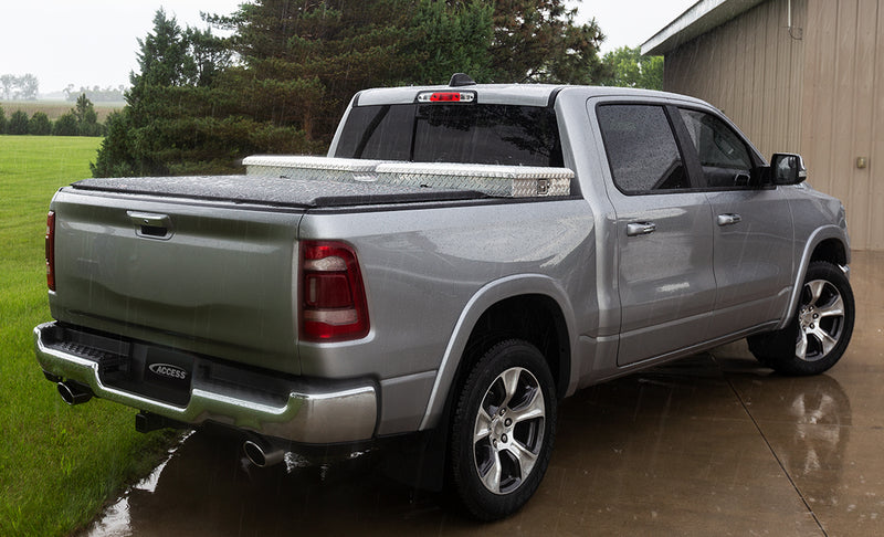 Access Toolbox Edition roll-up tonneau cover on a pickup bed: silver crew cab pickup in the rain, black roll-up cover closed behind an aluminum diamond-plate bed toolbox (truck-bed toolbox shown, not included)