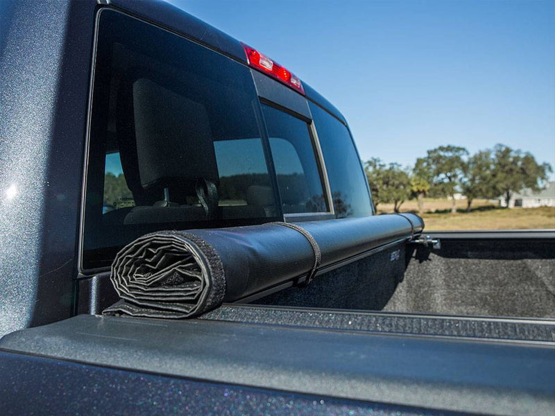 Close-up of the cover rolled and secured with its storage strap at the front of the bed