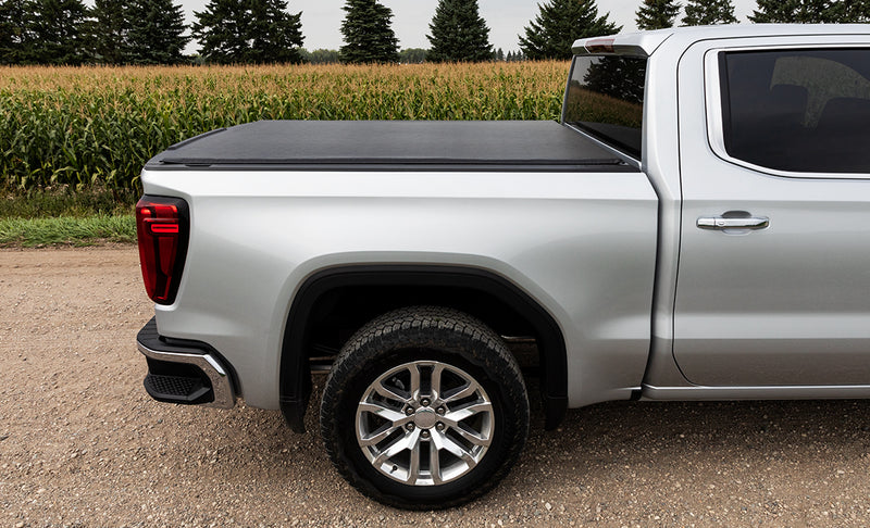 Access Vanish roll-up tonneau cover on a pickup bed: side view of a silver pickup beside a cornfield, black roll-up cover closed low over the bed