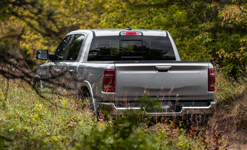 Access Vanish roll-up tonneau cover on a pickup bed: silver pickup on an overgrown trail seen from the rear, low-profile cover closed flush over the bed