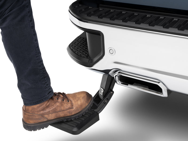 A work boot stands on the deployed BedStep below a white rear bumper
