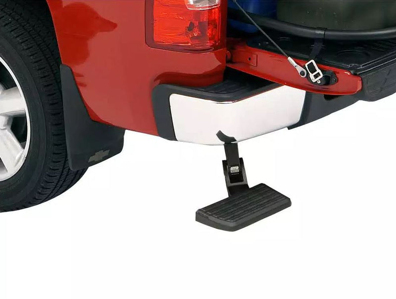 Earlier-style bed step deployed under the chrome rear bumper of a red pickup with the tailgate down