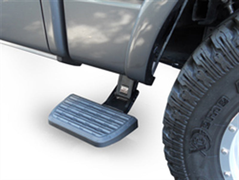 Side bed step deployed ahead of the rear wheel of a gray pickup with off-road tires