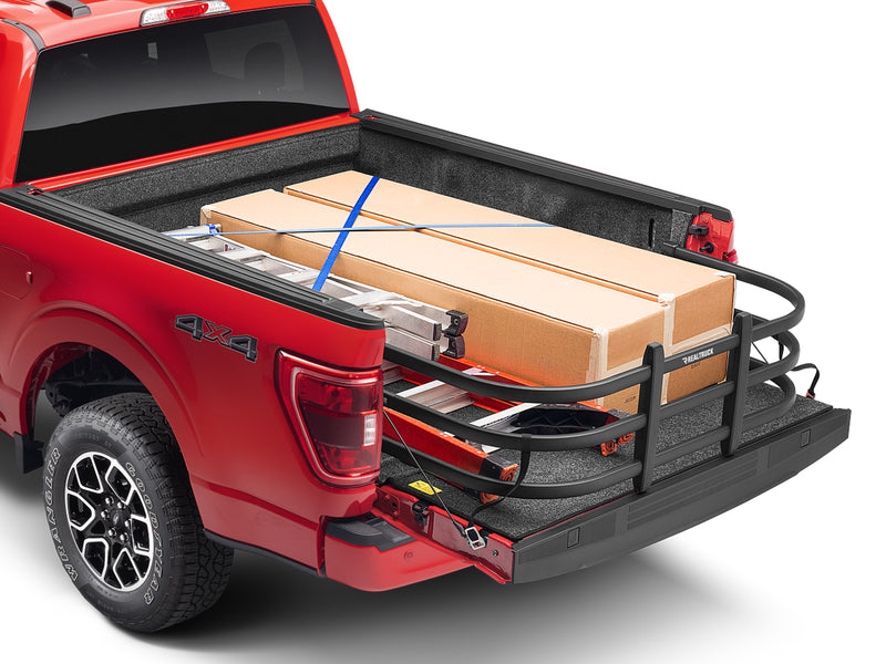 BedXTender HD Max extended over the lowered tailgate of a red pickup, holding boxed cargo and a ladder