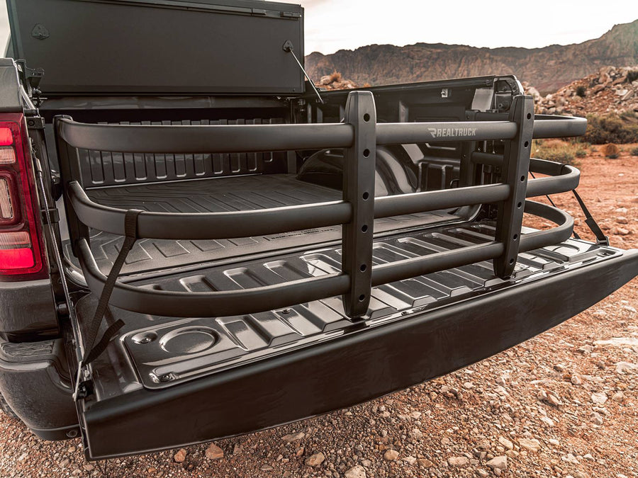 BedXTender HD Max extended over the lowered tailgate of a dark pickup, with desert mesas behind
